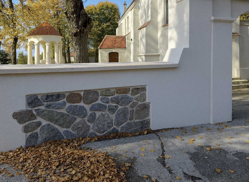 Widok odrestaurowanego fragmentu muru z bramką po zakończeniu prac